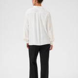 Person wearing a white shirt and black pants on a white background