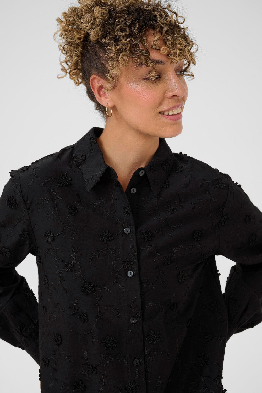 Woman wearing a black embroidered shirt against a white background