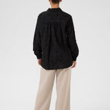 Person wearing a black shirt and beige pants on a white background