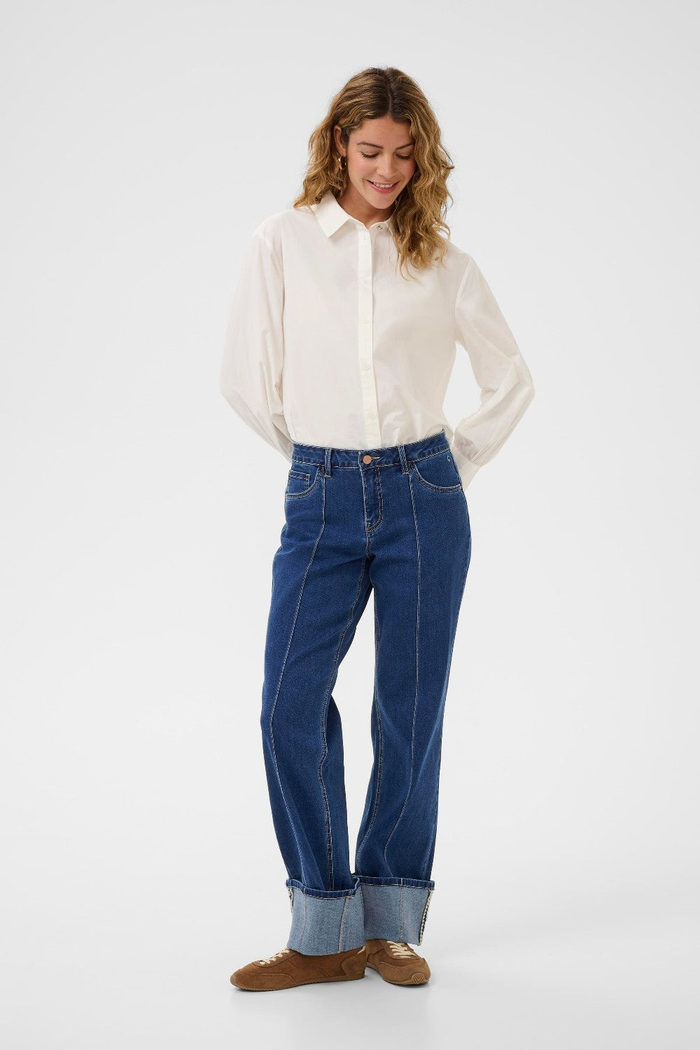 Woman wearing a white shirt and blue jeans on a white background