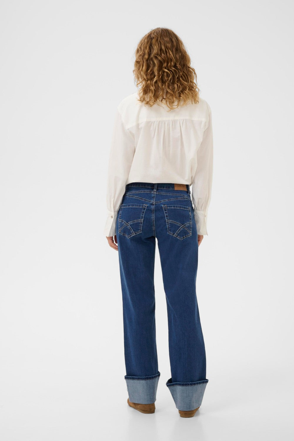 Woman wearing blue jeans and a white blouse on a white background