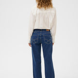 Woman wearing blue jeans and a white blouse on a white background