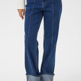 Person wearing blue jeans and brown shoes on a white background
