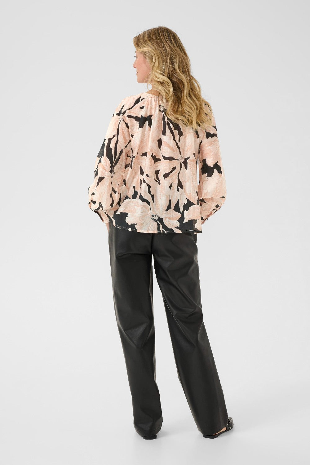 Woman wearing a floral blouse and black pants on a white background