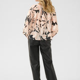 Woman wearing a floral blouse and black pants on a white background