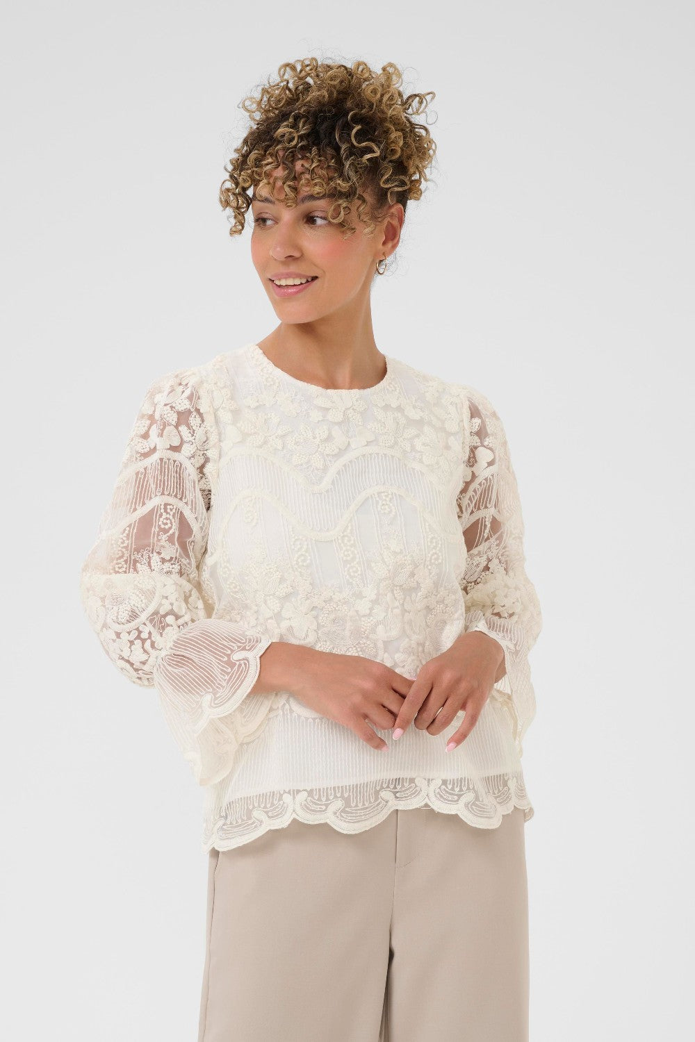 Woman wearing a white lace top with a plain background