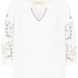 White top with floral embroidery on a white background