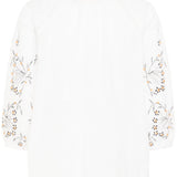 White top with floral embroidery on a white background