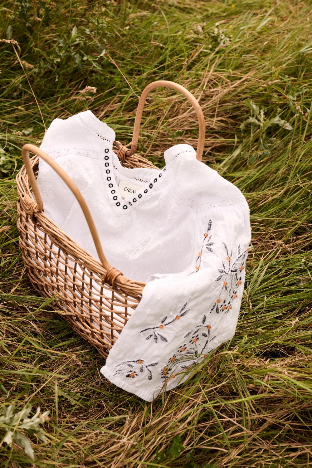 Wicker basket with white clothes on a grassy background