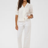 Woman wearing a white outfit with a plain background