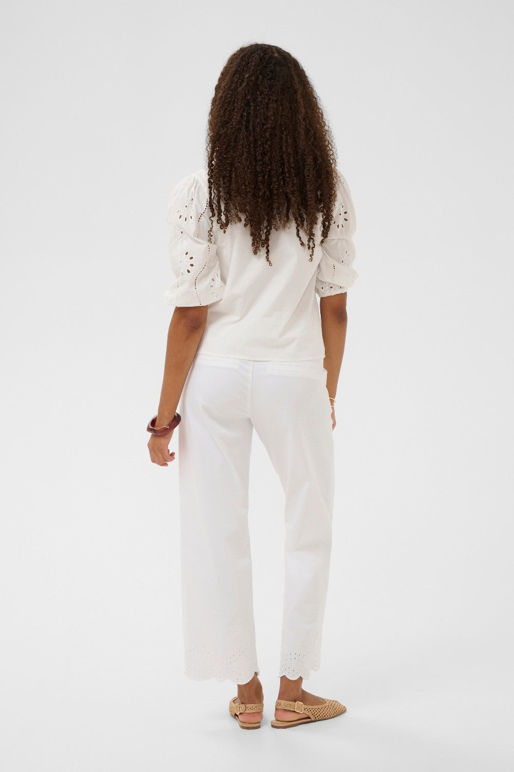 Person wearing a white outfit with details on a plain background