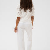 Person wearing a white outfit with details on a plain background