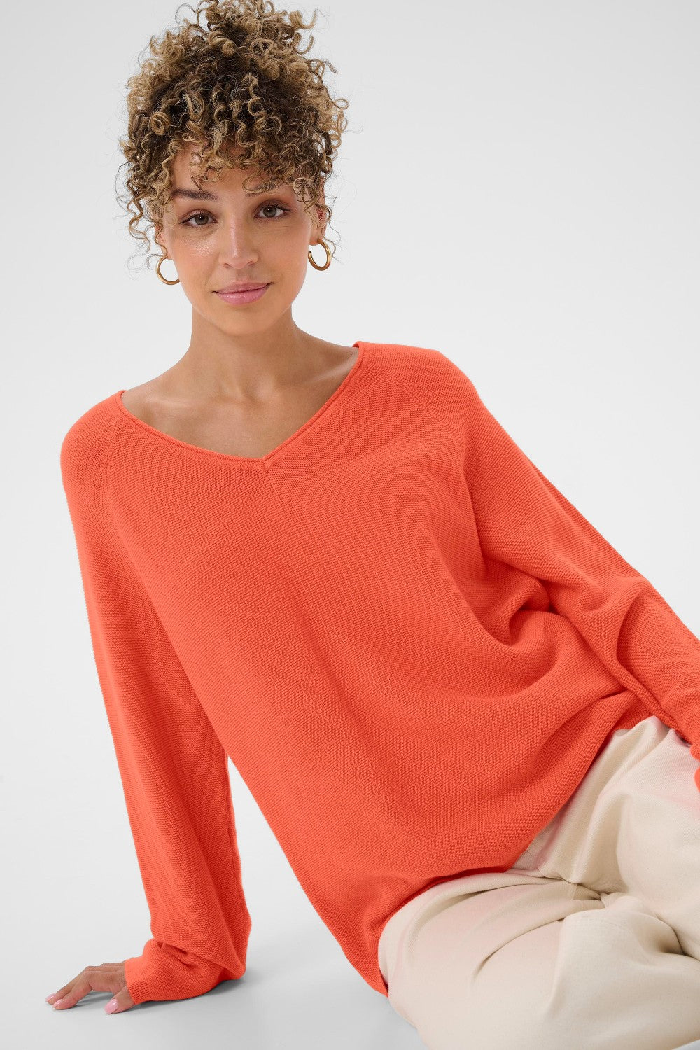 Woman wearing an orange sweater against a white background