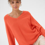 Woman wearing an orange sweater against a white background