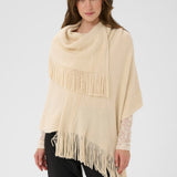 Woman wearing a beige poncho with fringe details on a white background