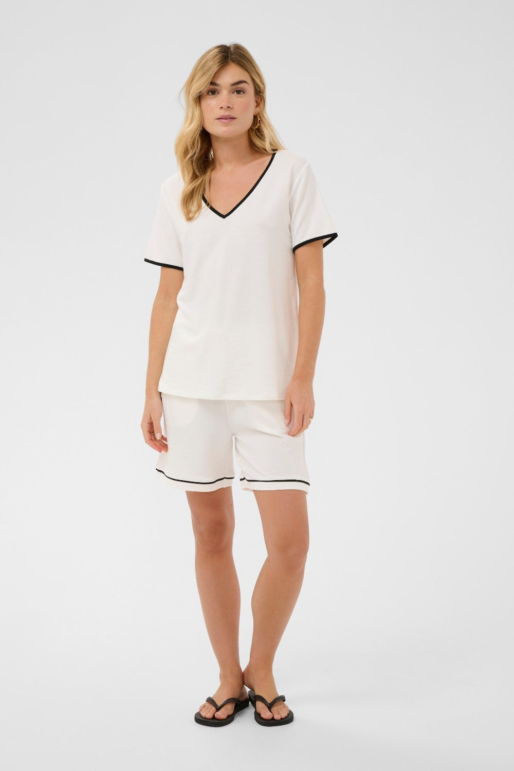 Woman wearing a white outfit with black trim on a white background