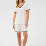 Woman wearing a white outfit with black trim on a white background