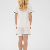 Person wearing a white outfit with black trim on a white background