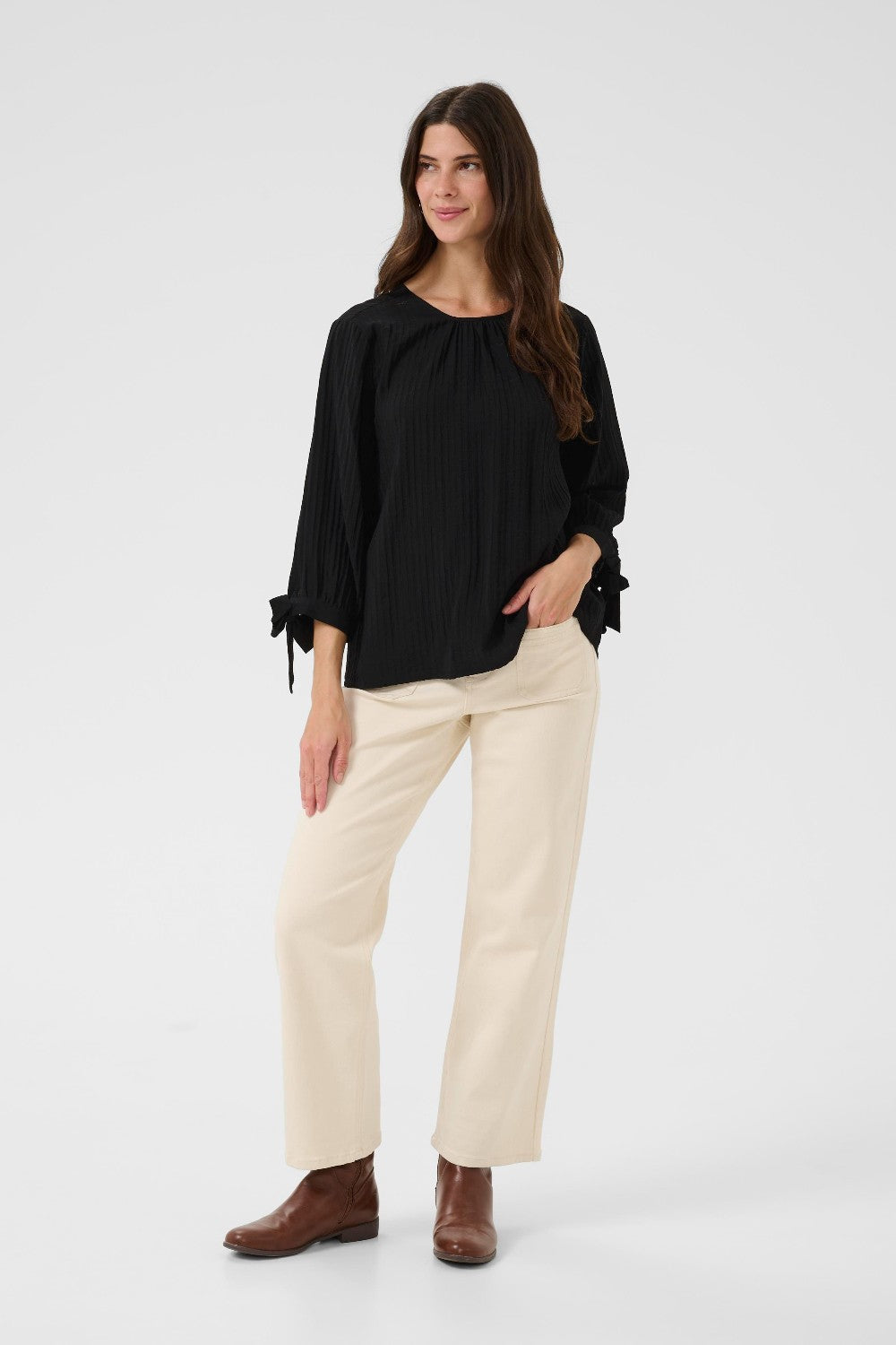 Woman wearing a black top and beige pants on a white background