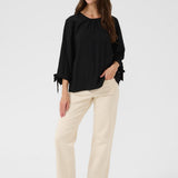 Woman wearing a black top and beige pants on a white background