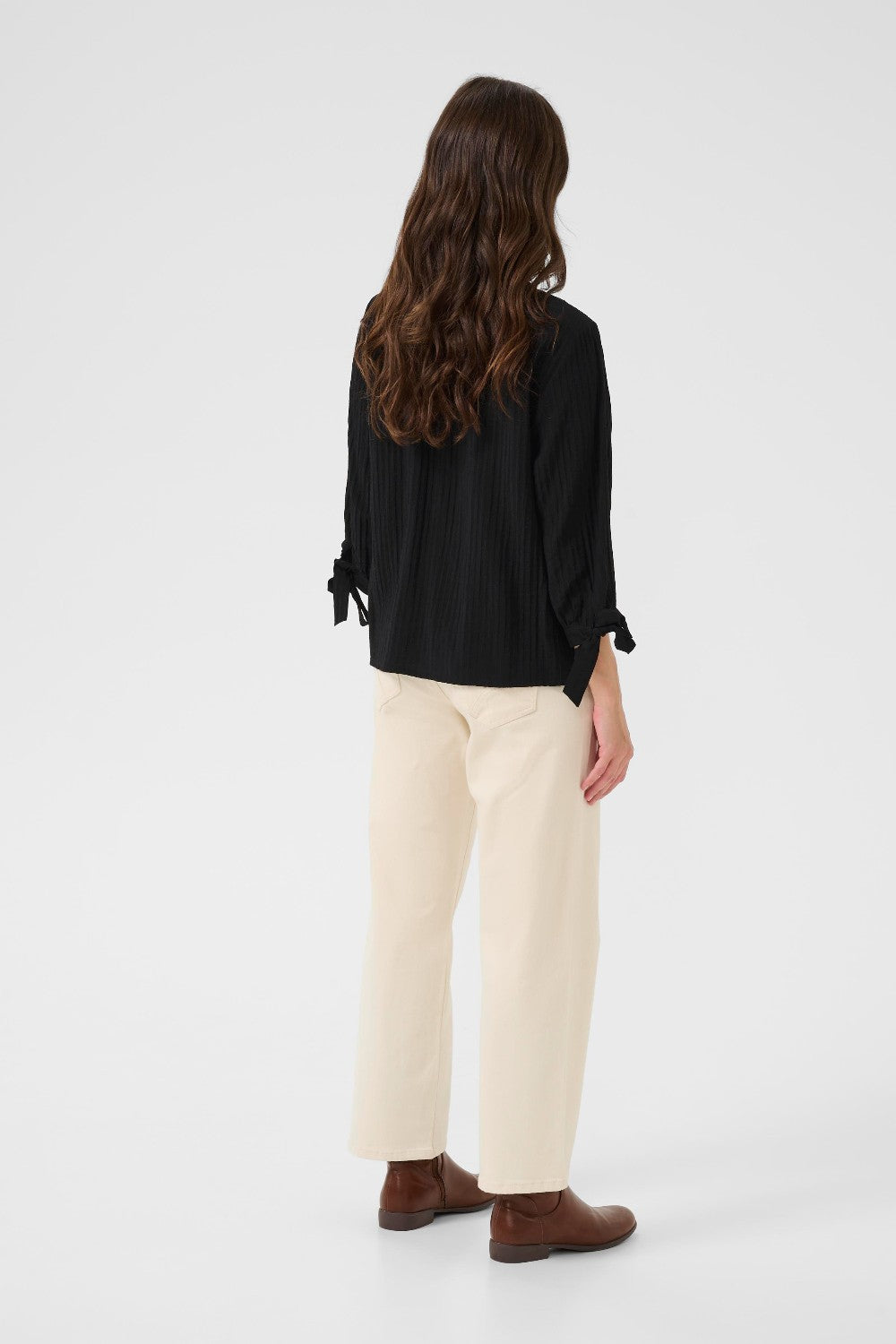 Woman wearing a black blouse and beige pants on a white background