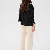 Woman wearing a black blouse and beige pants on a white background