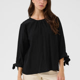 Woman wearing a black blouse with beige pants on a white background