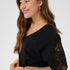 Woman wearing a black top with lace sleeves on a white background