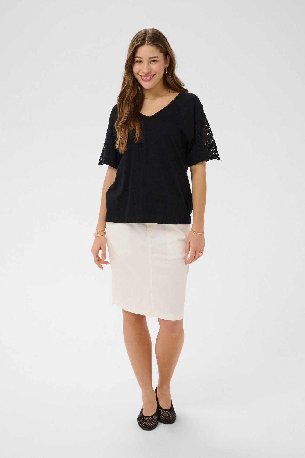 Woman wearing a black top and white skirt on a white background