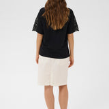 Woman wearing a black top with lace sleeves and a white skirt on a white background