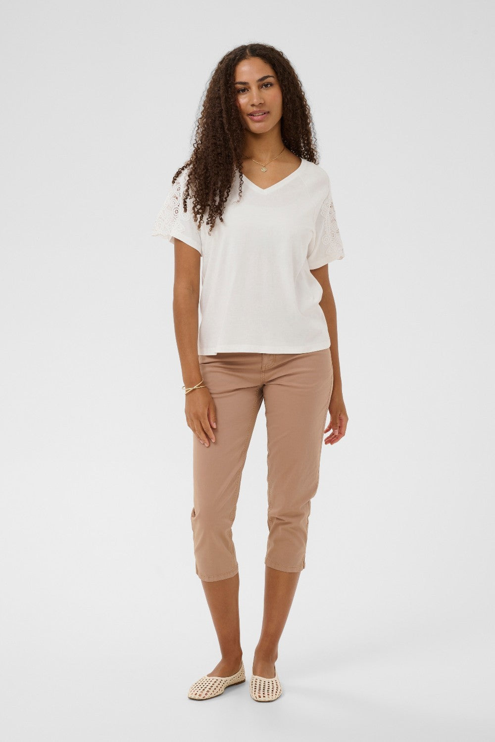 Woman wearing a white top and beige pants on a white background