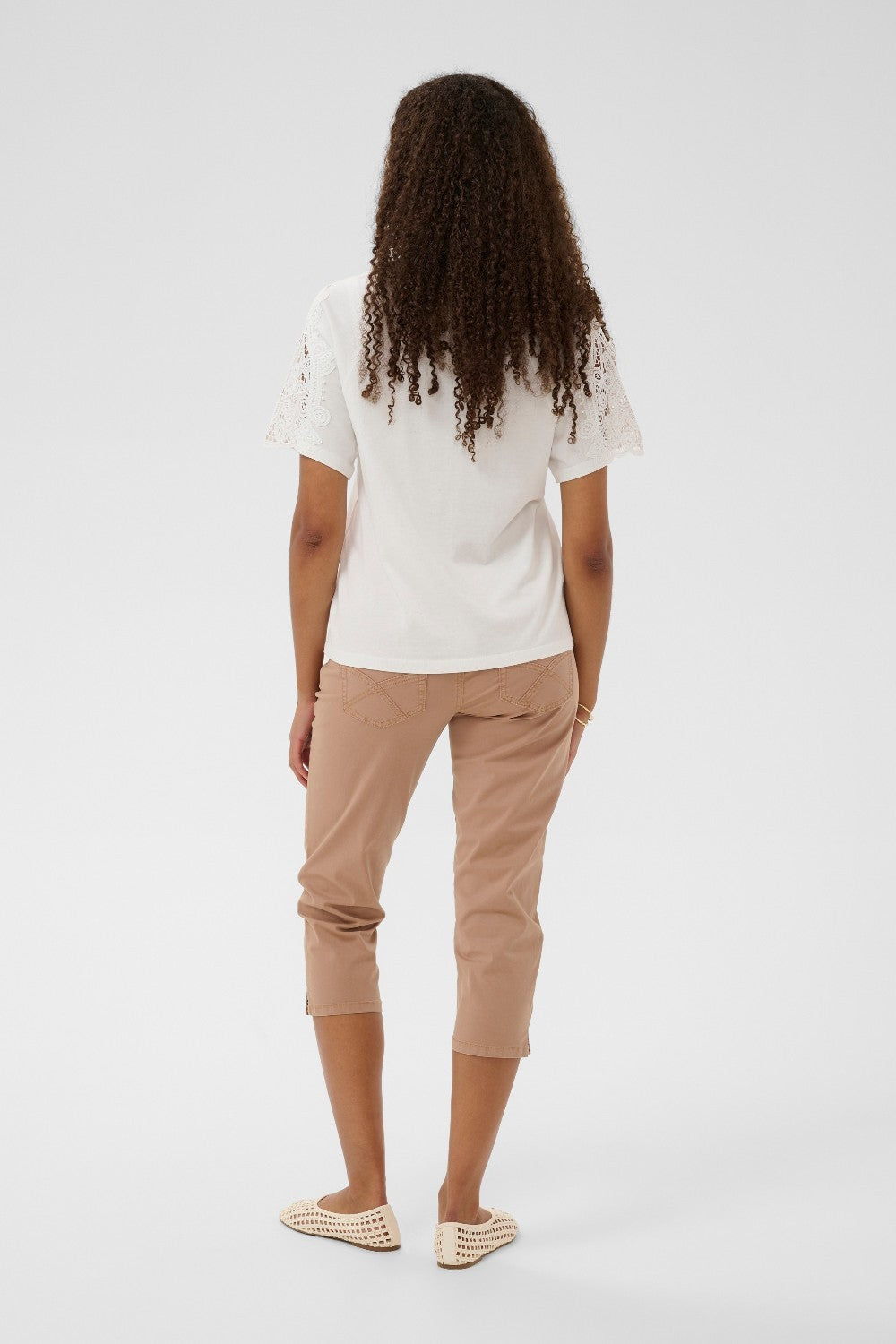 Person wearing a white top and beige pants on a white background