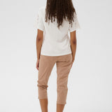Person wearing a white top and beige pants on a white background