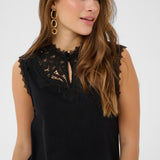Woman wearing a black sleeveless top with lace details on a white background