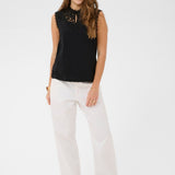 Woman wearing a black sleeveless top and white pants on a white background