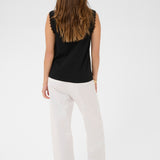 Person wearing a black sleeveless top and white pants on a white background