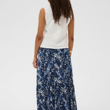 Woman wearing a white sleeveless top and blue floral skirt on a white background