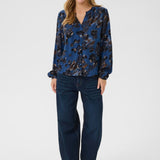 Woman wearing a blue floral blouse and dark jeans on a white background