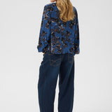 Woman wearing a blue floral shirt and jeans on a white background