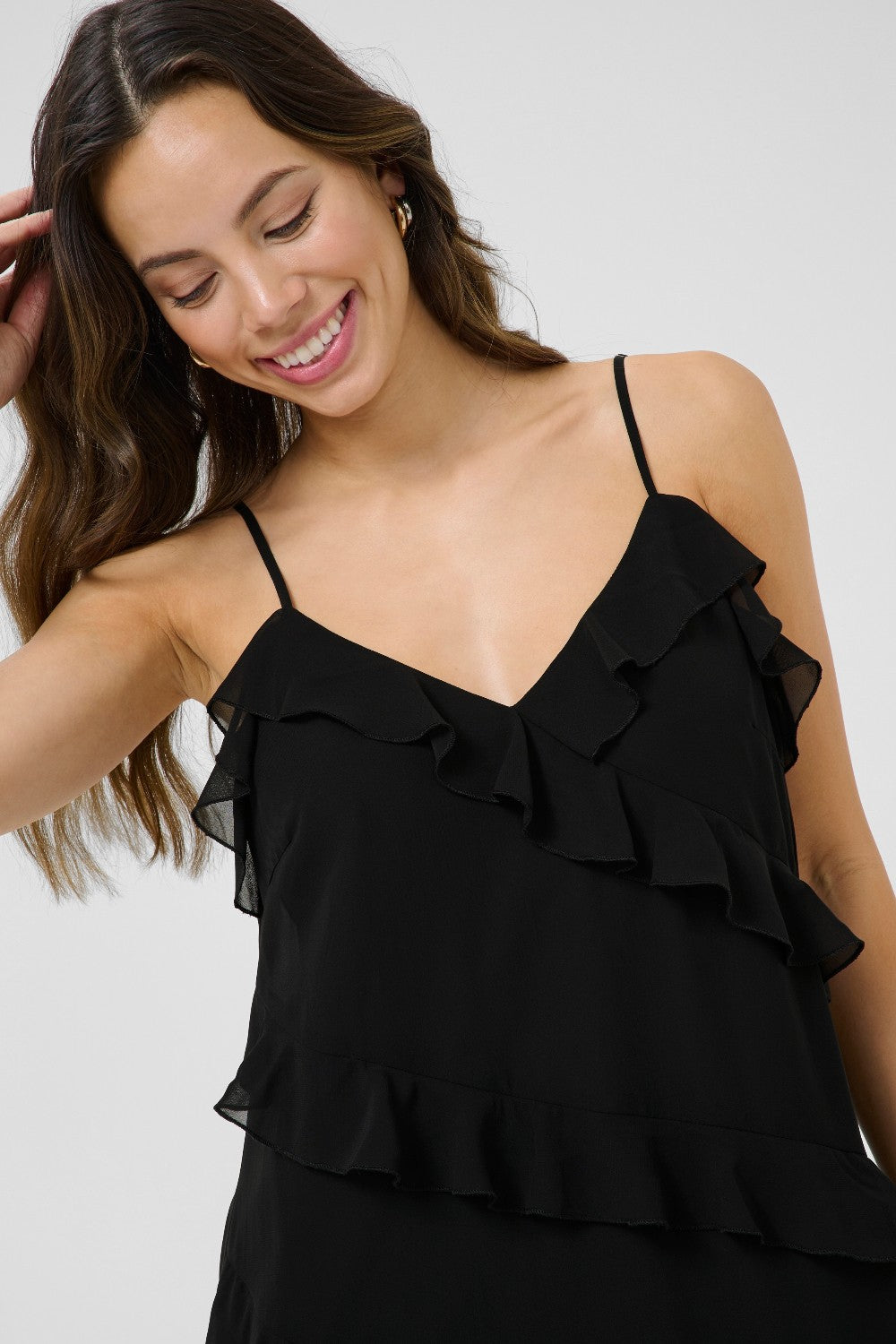Woman wearing a black ruffled top against a white background