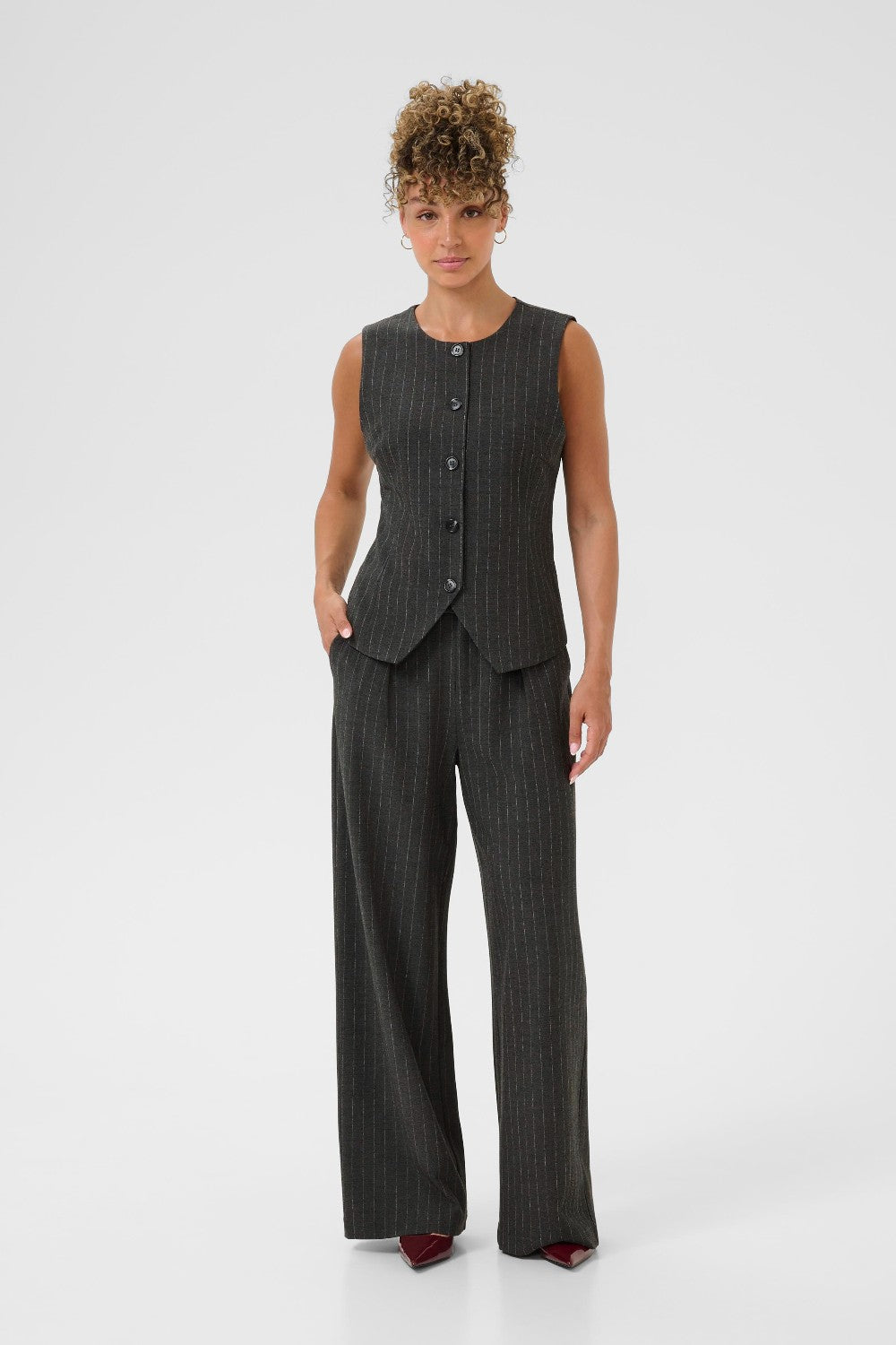 Woman wearing a gray pinstripe vest and pants on a white background
