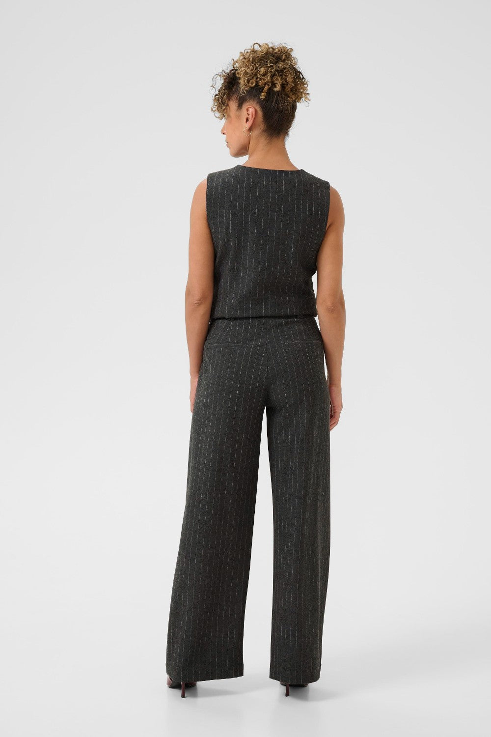 Person wearing a sleeveless top and high-waisted pants on a white background