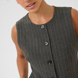 Woman wearing a gray pinstripe dress with buttons on a white background