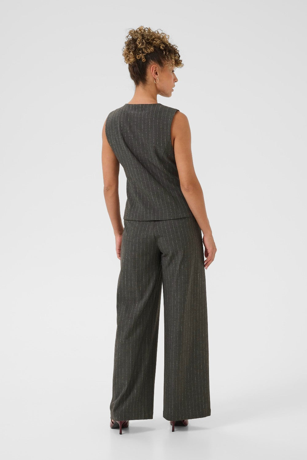 Woman wearing a grey pinstripe sleeveless top and wide-leg pants on a white background