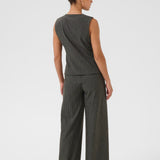 Woman wearing a grey pinstripe sleeveless top and wide-leg pants on a white background