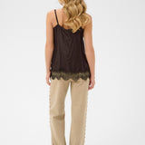 Woman wearing a brown lace-trimmed top and beige pants on a white background
