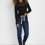 Woman wearing a black top, blue jeans, and brown shoes on a white background