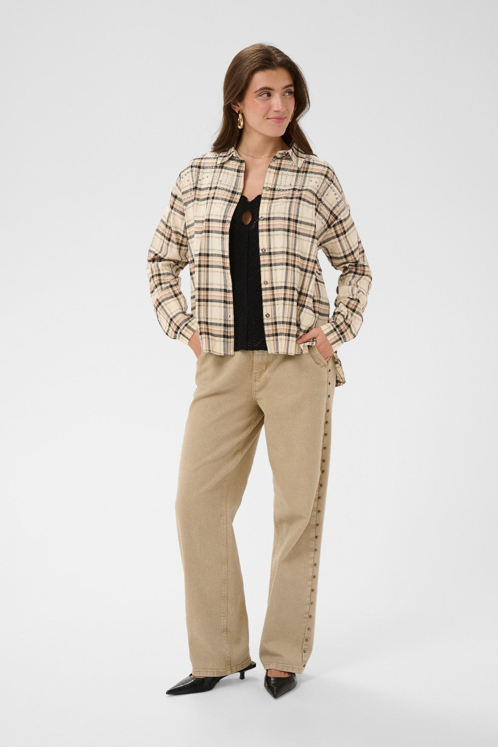 Woman wearing a plaid jacket and beige pants on a white background