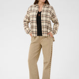Woman wearing a plaid jacket and beige pants on a white background