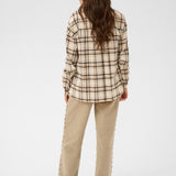 Woman wearing a plaid shirt and beige pants on a white background